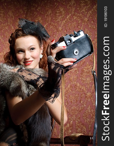 Young vintage woman with camera in old-style studio. Young vintage woman with camera in old-style studio