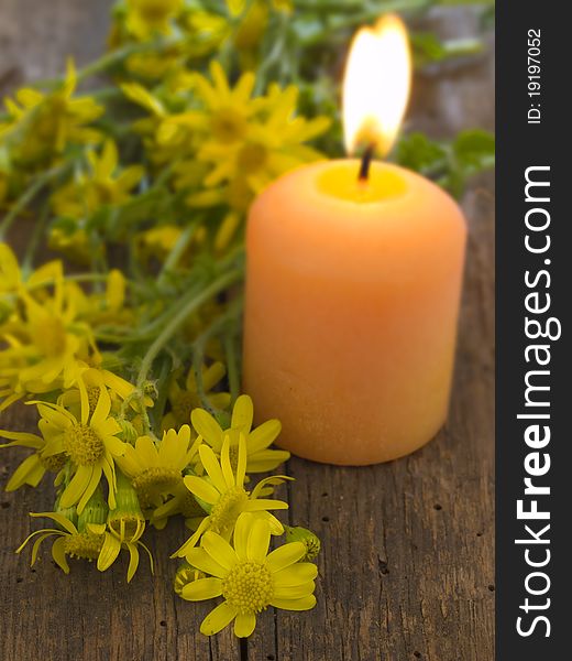With burning candle and yellow flowers over wood background. With burning candle and yellow flowers over wood background