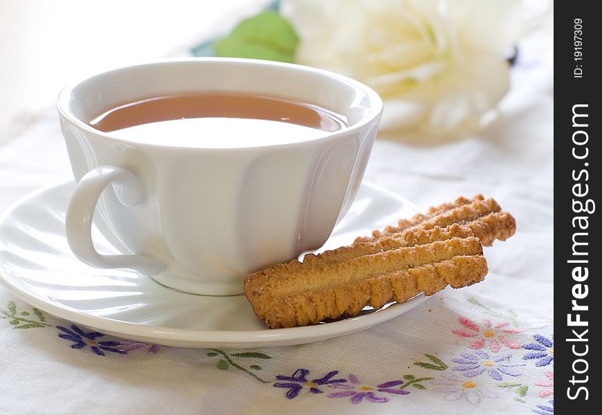 A cup of tea with cookies and tulip