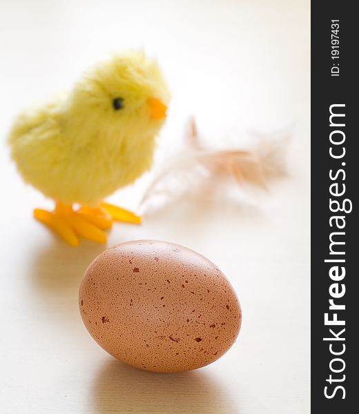 Ecological brown egg with chicken toy on background