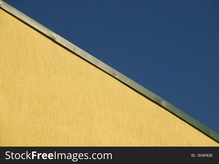 Fragment of the yellow roof of the build and blue sky. Fragment of the yellow roof of the build and blue sky