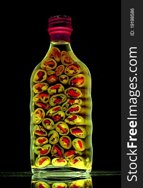 High vitality image of a bottle of sliced green peppers against a black background. High vitality image of a bottle of sliced green peppers against a black background