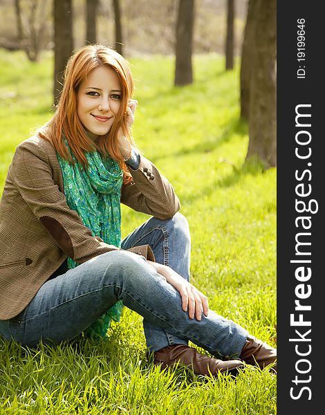 Beautiful girl sitting at green grass at park.