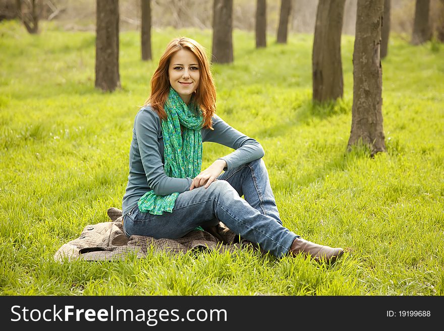 Beautiful girl sitting at green grass at park.