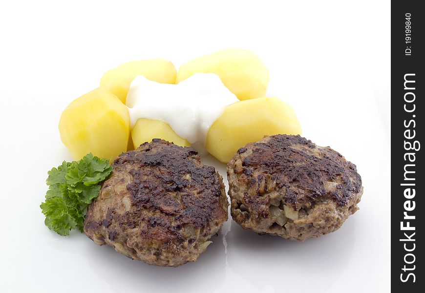 Two meatballs with potatoes parsley and some cream on the top of the potatoes. Two meatballs with potatoes parsley and some cream on the top of the potatoes