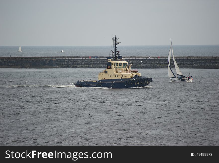 Powerful tug boat passing small yacht on river Tyne. Powerful tug boat passing small yacht on river Tyne