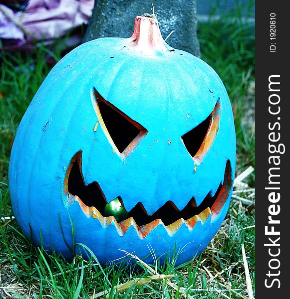 A blue jack-o-latern on grass with a tree behind it. A blue jack-o-latern on grass with a tree behind it.