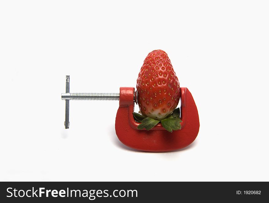 Strawberry clamped in red vice with copy space. Strawberry clamped in red vice with copy space