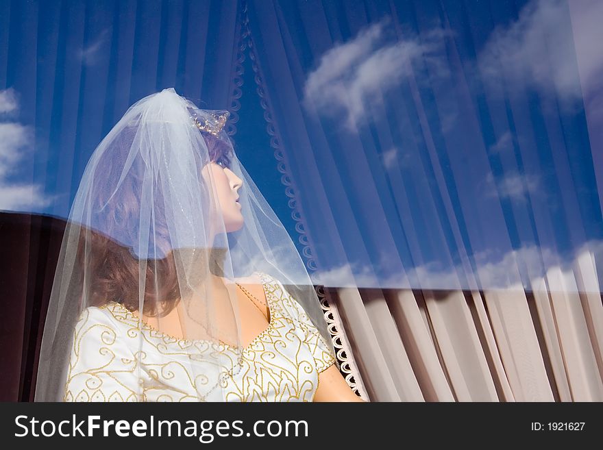 A blue sky with some clouds are reflected off the window of a bridal store. A blue sky with some clouds are reflected off the window of a bridal store.