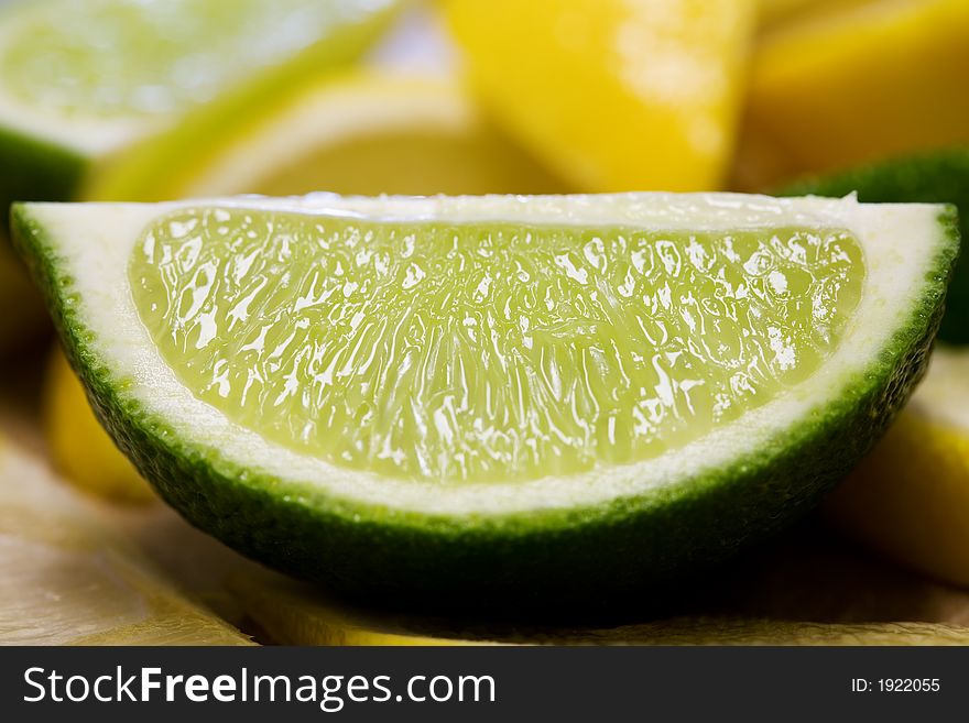 Closeup view of a freshly cut lime amongst other limes and lemons. Top lit and shows lots of detail.