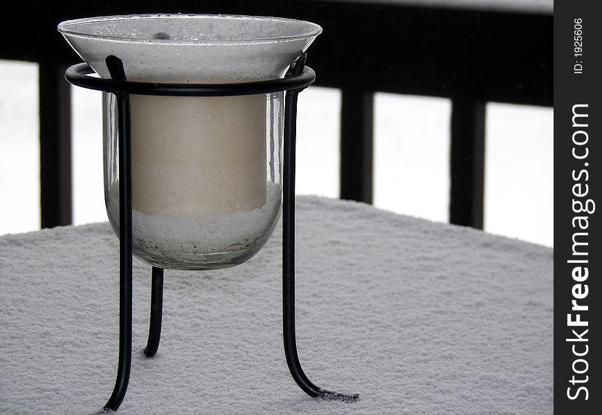 Snow covered candle on a glass table top. Snow covered candle on a glass table top