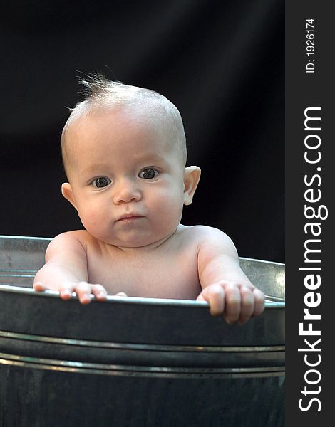 Image of baby sitting in a galvanized tub. Image of baby sitting in a galvanized tub