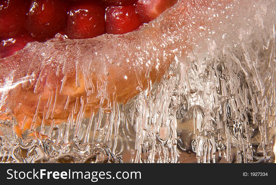 Red pomgranate frozen into a piece of curved ice. Red pomgranate frozen into a piece of curved ice