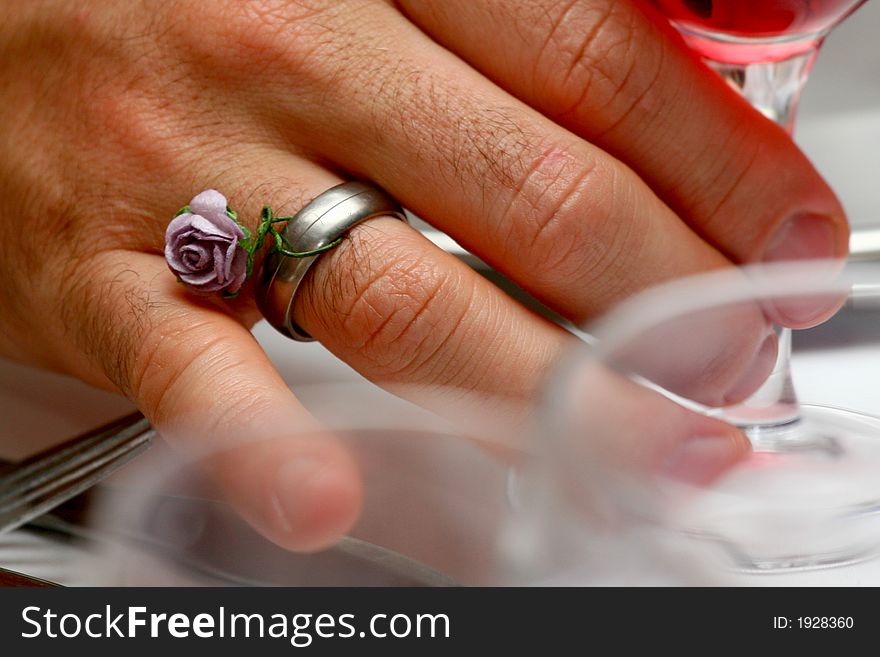 A hand with a wedding ring on decorated by a flower. A hand with a wedding ring on decorated by a flower