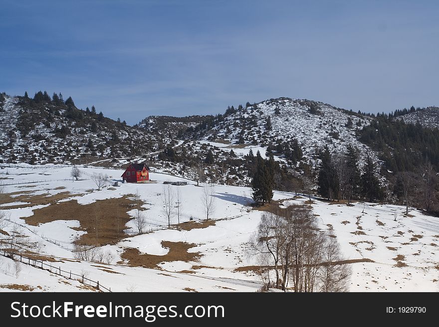 Winter landscape with red house and blue sky