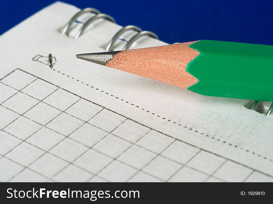 Green pencil and notebook on blue background