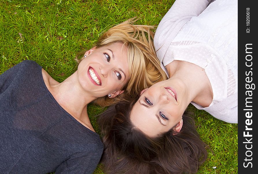 Two beautiful girls lying in the grass and laughing. Two beautiful girls lying in the grass and laughing.