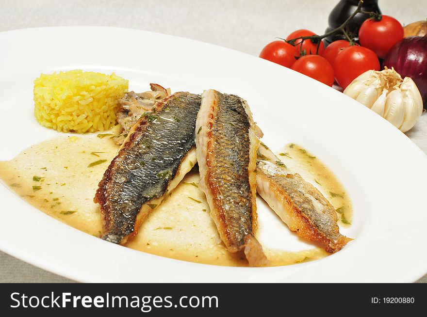 Dorada fish with risotto on a white plate