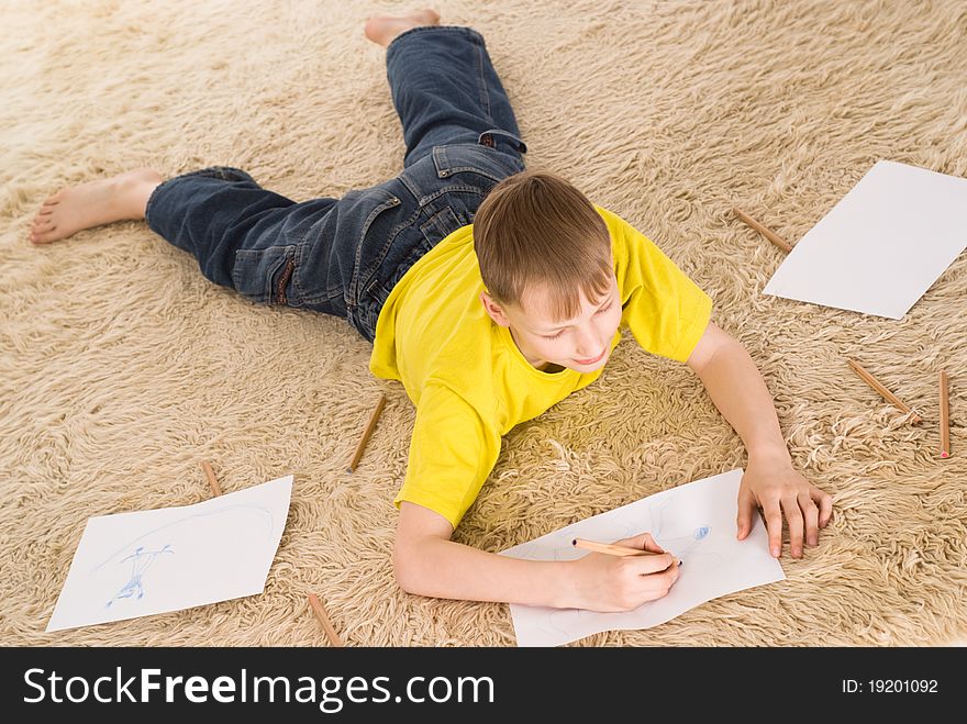 Young boy drawing on the carpet on white