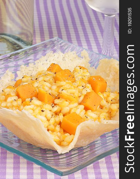 Cheese basket filled with risotto and pumpkin over a glass dish. Cheese basket filled with risotto and pumpkin over a glass dish.