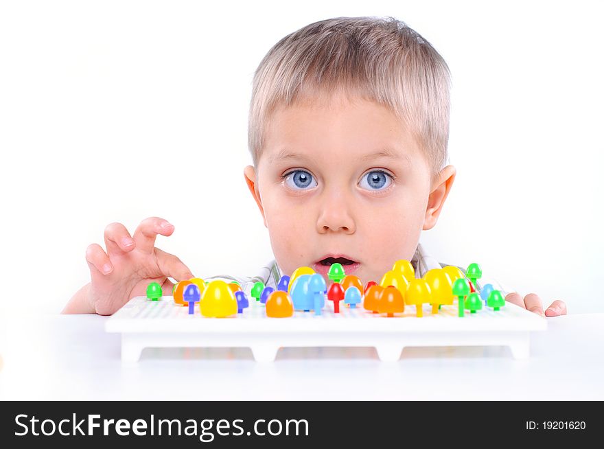 Little boy playing with multicolored mosaic isolated on a white background. Little boy playing with multicolored mosaic isolated on a white background