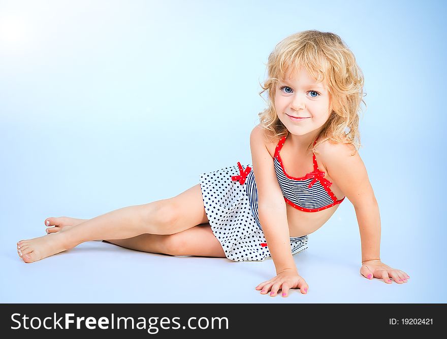 Adorable smiling playful girl 4 years old lying on blue studio background