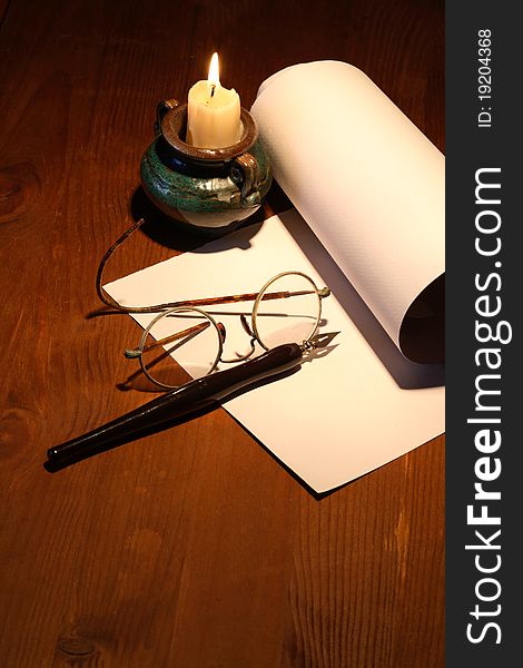 Scroll and old spectacles near lighting candle on wooden surface. Scroll and old spectacles near lighting candle on wooden surface