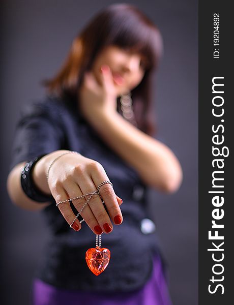 Young beautiful woman holding heart, isolated on dark background - focus on heart