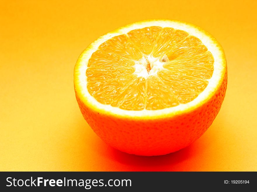 Half an orange lying on a yellow background