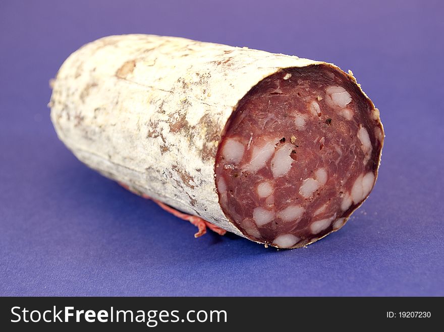 Milan salami cut in the foreground color background