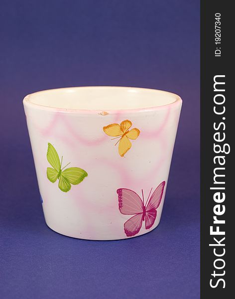 Decorated ceramic pot in the foreground on colored background