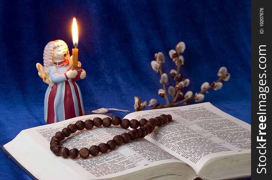 The bible, candle and branch willow at a blue background