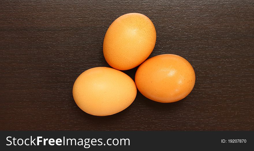 Three chicken eggs on brown wood texture. Three chicken eggs on brown wood texture