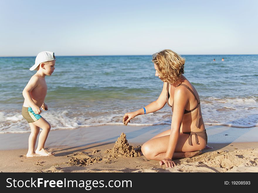 Mom and son building a sand castle on a beach