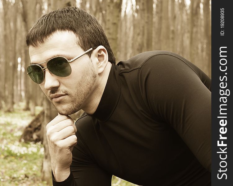 Young man in black clothes and sunglasses closeup portrait