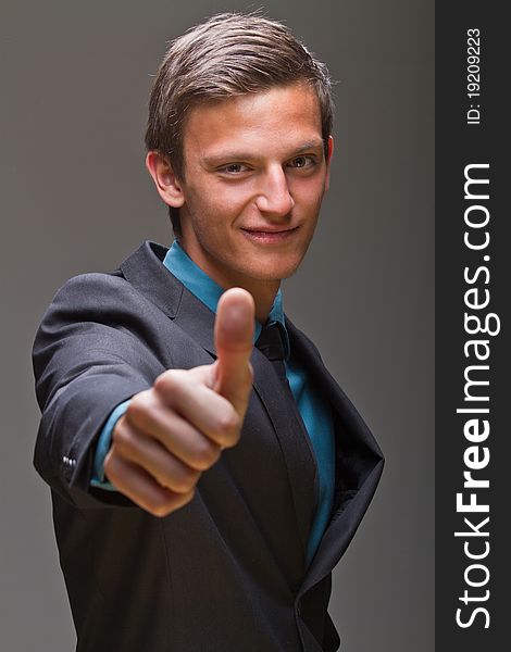 Young businessman showing a thumbs up sign. Expressing positive attitude. Young businessman showing a thumbs up sign. Expressing positive attitude.