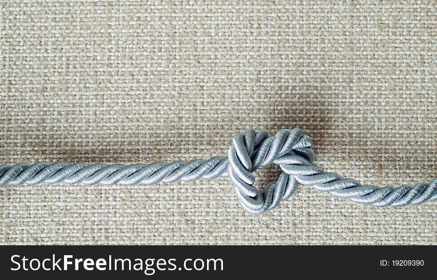 Light gray Rope tie a heart shape On cream fabric