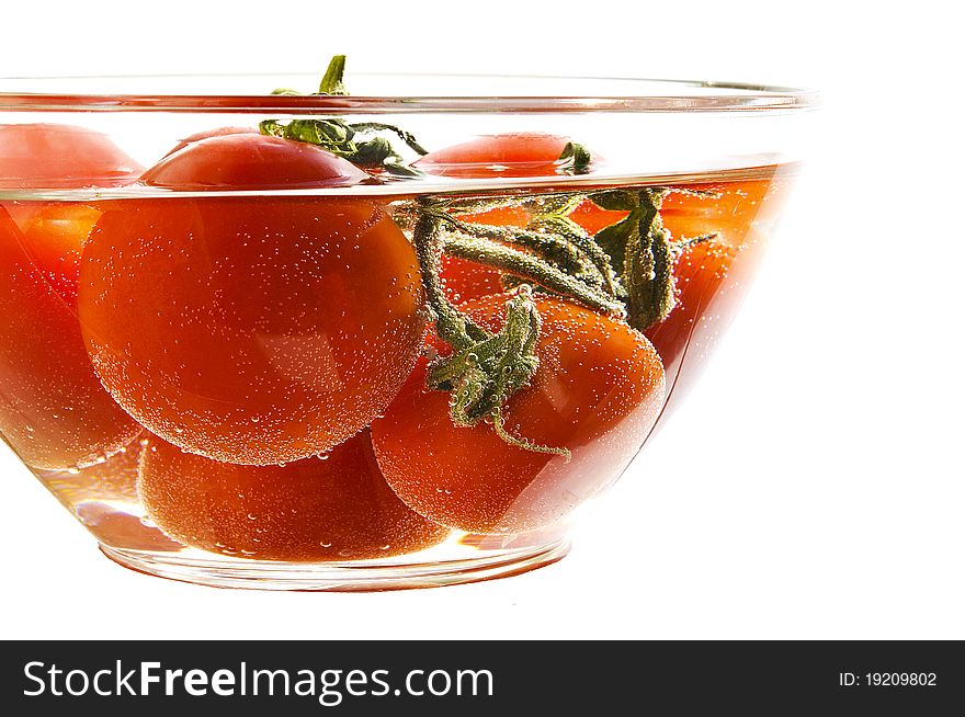 Red tomatoes in a plate with water on the white isolated background