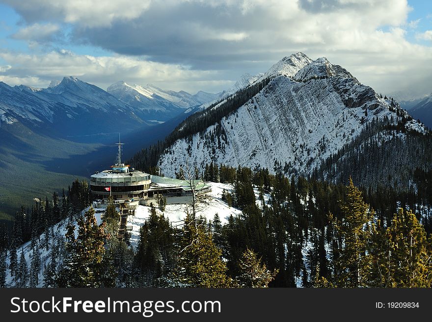 It was taken in Banff National Park. The mountain looks like a pyramid covered with white snow. The clouds in the sky cast long shadows on the other mountains far away. The building is a watch station. It was taken in Banff National Park. The mountain looks like a pyramid covered with white snow. The clouds in the sky cast long shadows on the other mountains far away. The building is a watch station.