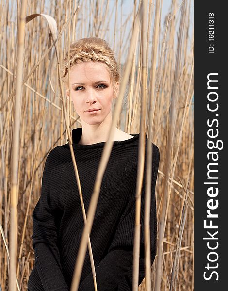 Outdoor portrait of young beautiful blond slim girl in the reed zone of the park. Outdoor portrait of young beautiful blond slim girl in the reed zone of the park