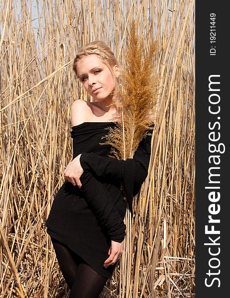 Outdoor portrait of young beautiful blond slim girl in the reed zone of the park. Outdoor portrait of young beautiful blond slim girl in the reed zone of the park