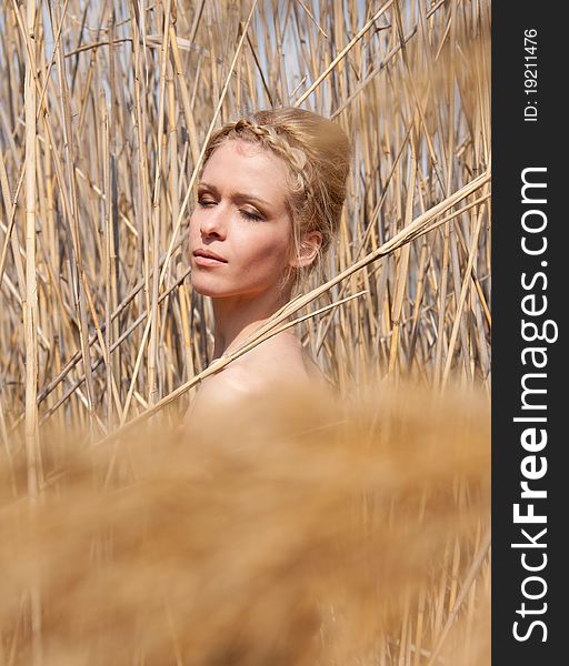 Outdoor portrait of young beautiful blond slim girl in the reed zone of the park. Outdoor portrait of young beautiful blond slim girl in the reed zone of the park