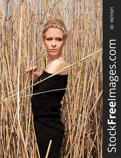 Outdoor portrait of young beautiful blond slim girl in the reed zone of the park. Outdoor portrait of young beautiful blond slim girl in the reed zone of the park