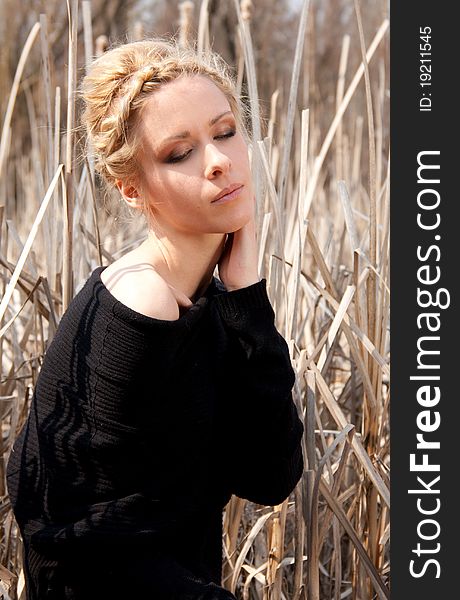 Outdoor portrait of young beautiful  blond slim girl in the reed zone of the park. Outdoor portrait of young beautiful  blond slim girl in the reed zone of the park