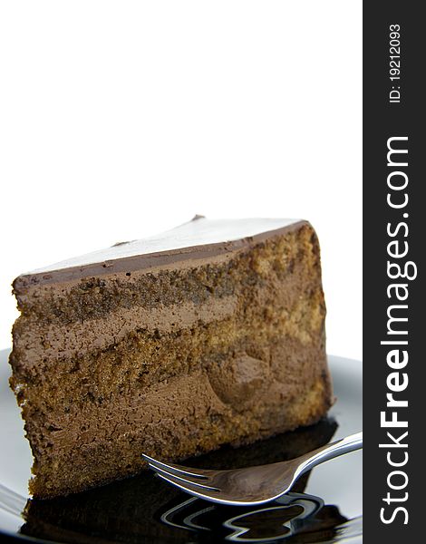 Slice of chocolate cake on a black plate with fork