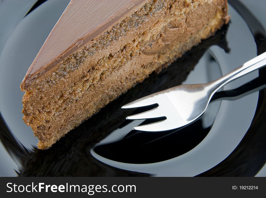 Slice of chocolate cake on a black plate with fork. Slice of chocolate cake on a black plate with fork