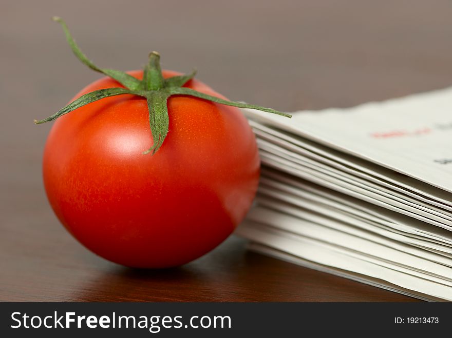 Red tomato on a table with a newspappers