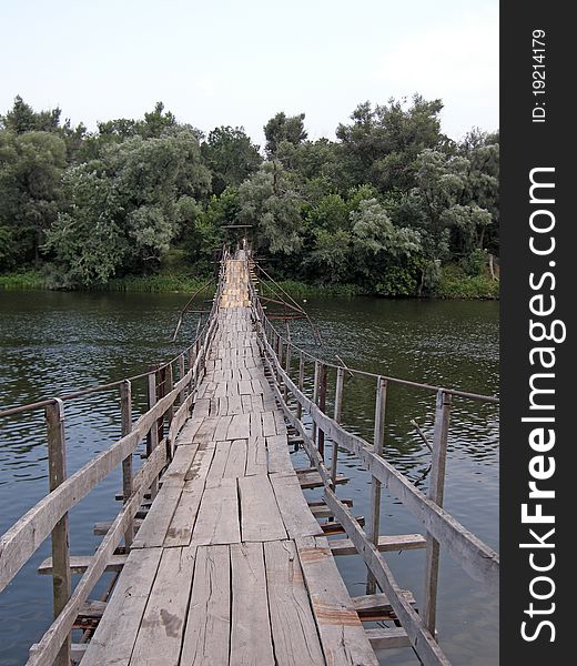 Old wooden footbridge over river with forest on background. Old wooden footbridge over river with forest on background