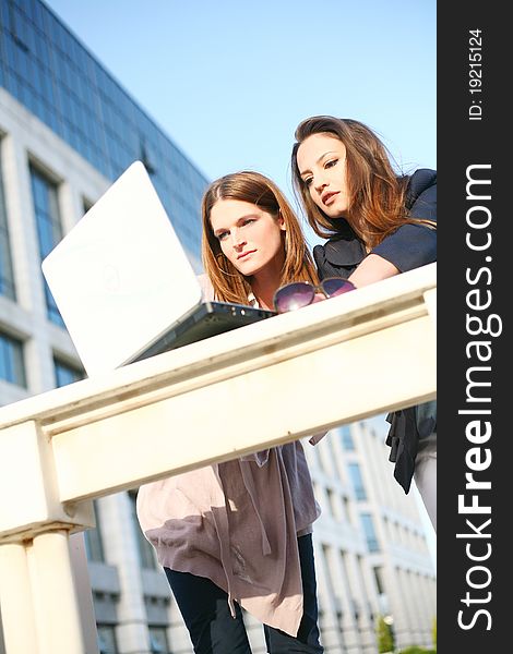 Beautiful young girls outside with laptop standing. Beautiful young girls outside with laptop standing