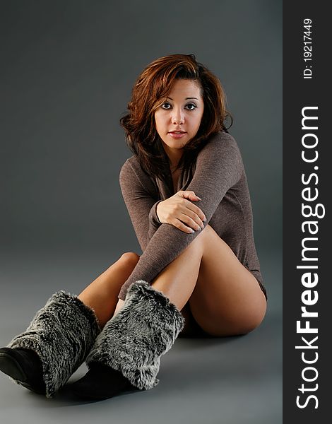 Young woman sitting on floor wearing her winter boots and a sweater. Young woman sitting on floor wearing her winter boots and a sweater.